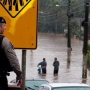 Imagem mostra policial militar da BM em frente a uma área inundada