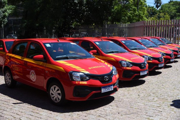 Viaturas vermelhas com uma faixa amarela nas laterais, entregues ao Corpo de Bombeiros, aparecem dispostas lado a lado no pátio da sede da corporação.