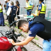 Servidor do IGP faz perícia em motocicleta. Ao fundo, outros agentes do IGP e da EPTC.