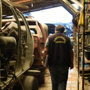 Servidor utilizando colete com a inscrição "Fiscalização Ambiental" às costas caminha entre as peças do ferro-velho vistoriado em Parobé.
