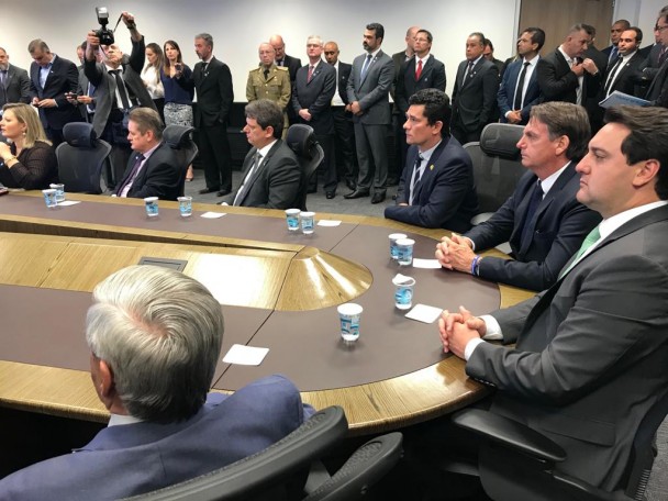 Mesa de reuniões em que se vê o vice-governador do RS, Ranolfo Vieira Júnior, o presidente da República, Jair Bolsonaro, e o ministro da Justiça e da Segurança Pública, Sergio Moro, além de outras autoridades.