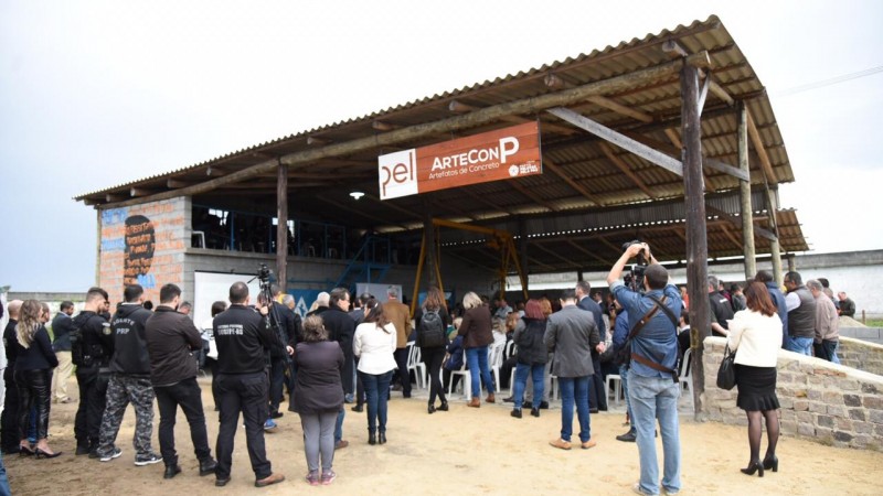 Pessoas aglomeradas em torno do galpão da fábrica de artefatos de concreto Artecon P, dentro do Presídio Regional de Pelotas.