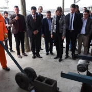 Autoridades observam detento retirar da prensa o primeiro bloco de concreto fabricado pela Artecon P após a inauguração, dentro do Presídio Regional de Pelotas.