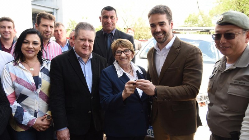 Governador, vice-governador e comandante-geral da BM aparecem em foto acompanhados de vereadora do Interior. Eduardo Leite entrega chave de veículo nas mãos da vereadora.