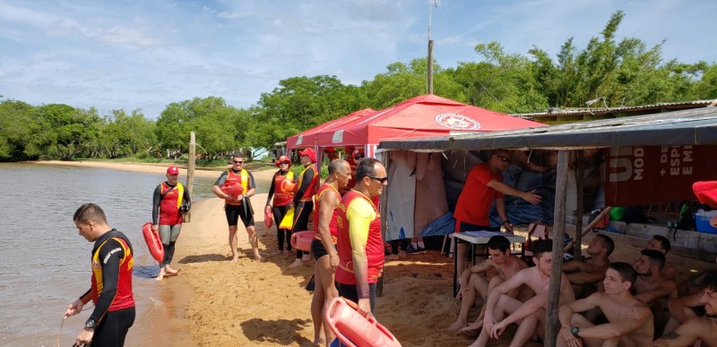 Guardas-Vidas dos Bombeiros em beira de praia, embaixo de gazebos, com equipamentos de salvamento.