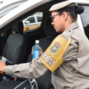 Brigadiana do CRBM limpa o volante de uma caminhonete com uma flanela com álcool gel.