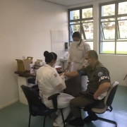 Duas profissionais da saúde aplicam ao teste em um policial militar.