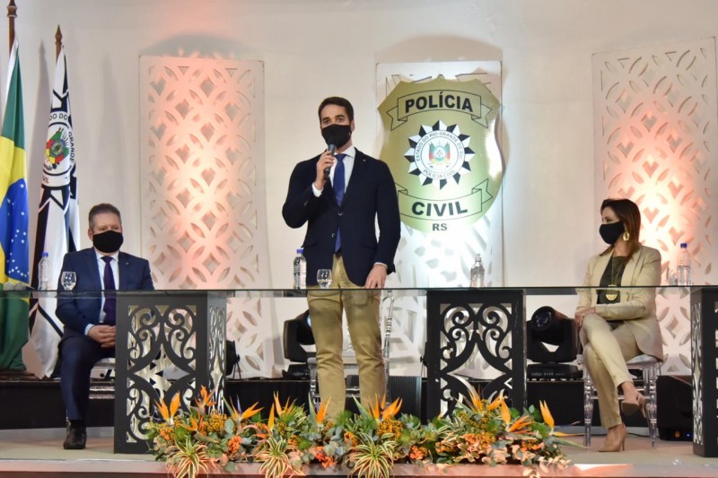 Eduardo Leite de pé e ao seu lado esquerdo, Delegado Ranolfo e a sua direita Delegada Nadine, ambos sentados