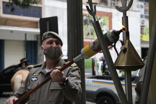 em imagem fechada, aparece o comandante geral da Brigada Militar, carregando a chama farroupilha e acendendo o candeeiro da instituição