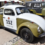 carro fusca, em verde oliva e branco, cores da Brigada Militar e o brasão da instituição na porta