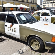 carro Opala, em verde oliva e branco, com a identificação da BM, estacionado ao lado de um fusca