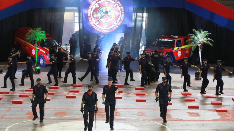 Muitos bombeiros em marcha, entrando no palco da formatura