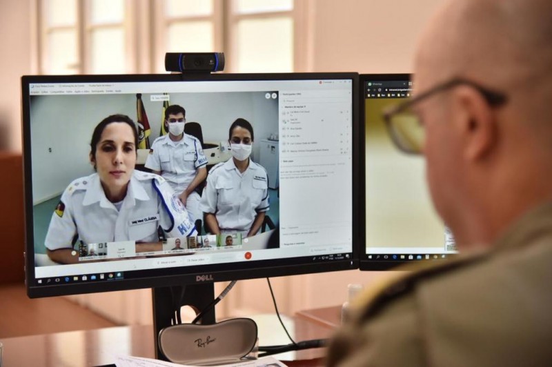 em uma imagem captada da tela do computador, três profissionais da saúde do quadro da BM participam da solenidade