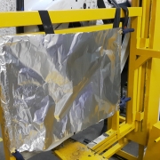 Folha de alumínio posicionada atrás de uma porta de veículo, presa a um suporte metálico amarelo, no final do corredor do estante de tiro onde são realizados testes balísticos.