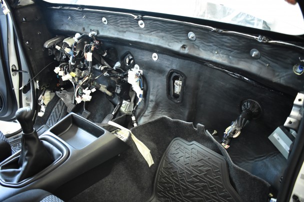 Visão do interior de um veículo que teve todo o painel desmontado. Fixada na lataria, as mantas pretas de aramida utilizadas na blindagem.