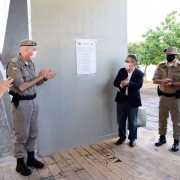 5 oficiais de pé, ao lado de uma placa instalada em um muro, aplaudindo a cerimônia e a nova sede do batalhão ambiental e seu comando.