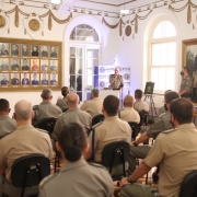 Sala onde foi feita a solenidade de despedida da coronel Cristine. Oficiais sentados e comandante-geral, coronel Rodrigo Mohr Picon, no pulpiter fazendo seu discurso