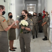 Coronel Cristine se despedindo de seus colegas, recebendo rosas brancas de suas colegas.