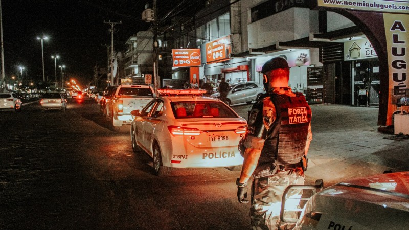 a noite um policial observa a movimentação na via próximo a viatura