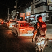 a noite um policial observa a movimentação na via próximo a viatura