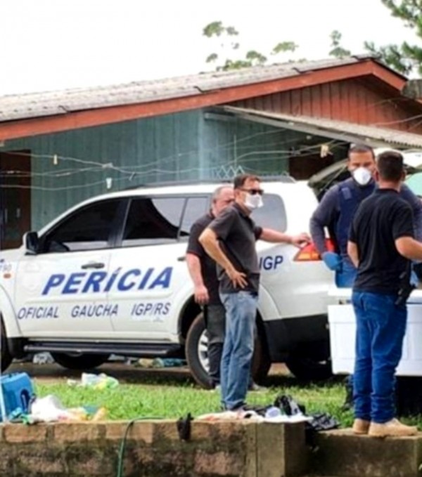 carro da perícia estacionado em frente a uma residencia de madeira, quatro pessoas, entre policias e peritos, conversam e observam a cena do crime