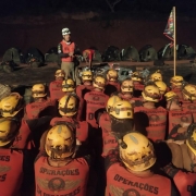 Os agentes estão sentadas no chão um do lado do outro enquanto um dos professores do curso permanece de pé em frente aos alunos. 