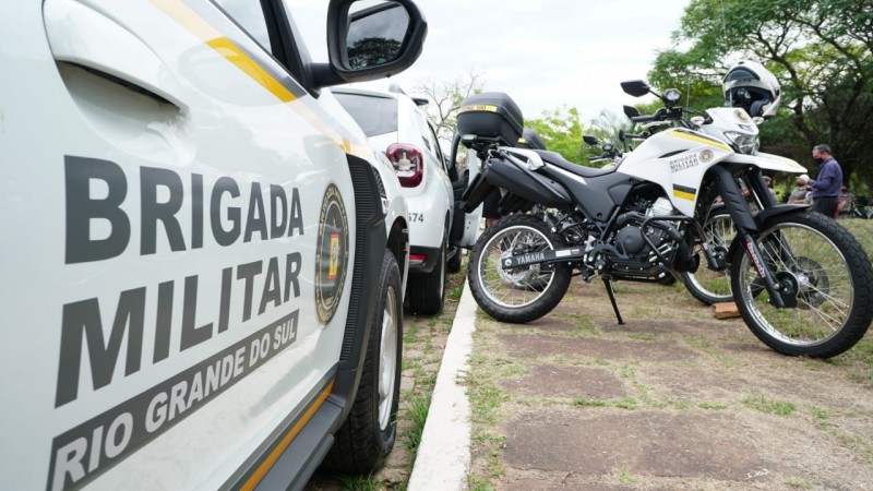 Nova viatura, ao lado de uma moto, com o logo da Brigada Militar, durante a entrega dos veículos.