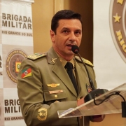 Comandante-geral da BM, coronel Vanius Cesar Santarosa, discursando em um púlpito com um banner da Brigada Militar ao fundo.