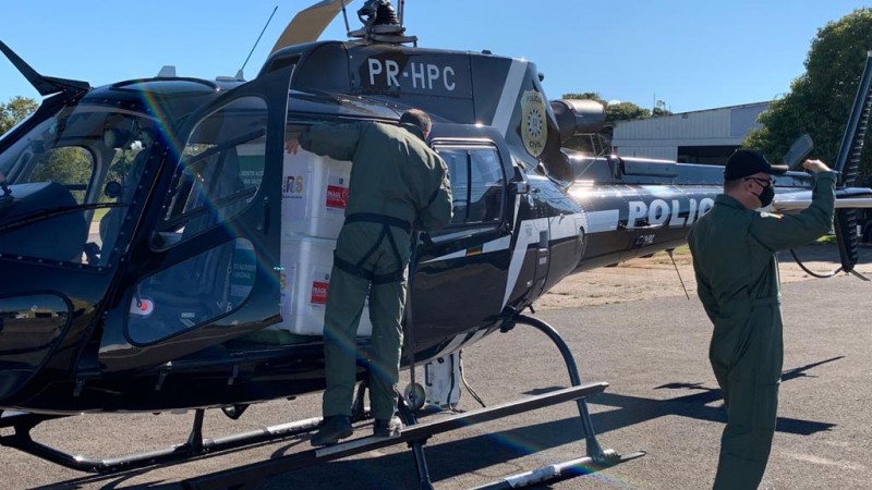 helicóptero da Polícia Civil com dois policiais da institução carregando os imunizantes