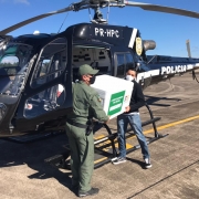 Policiais civis carregando vacina no helicóptero 