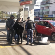 Policiais em um posto de gasolina conferindo uma bomba de combustível