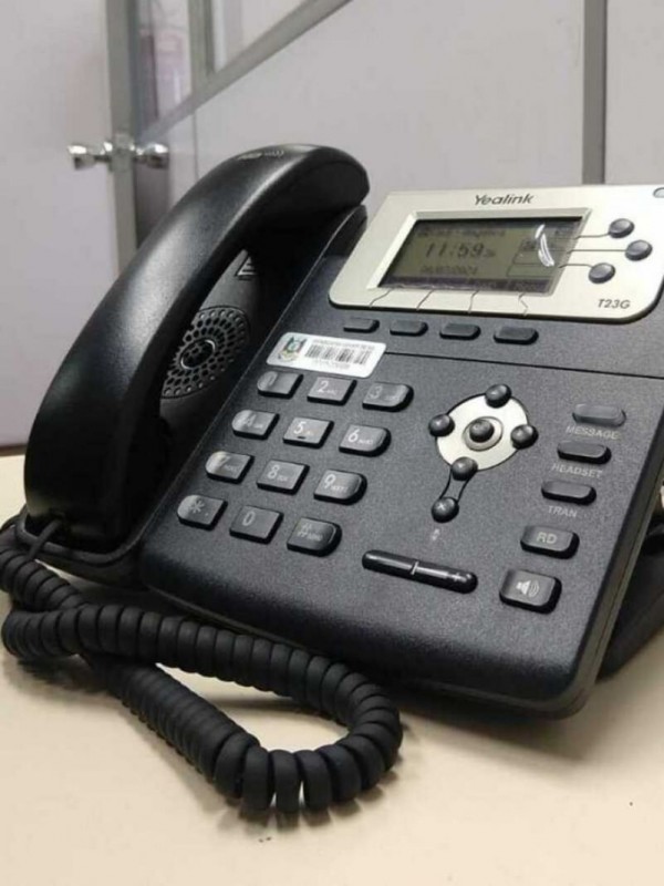 Foto de telefone fixo preto em cima de uma mesa.