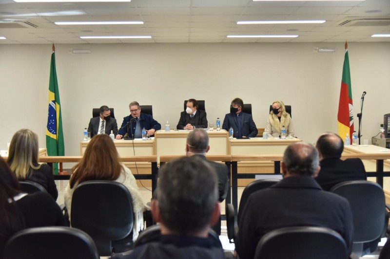 Pessoas sentadas diante de uma mesa de autoridades na qual estão o vice-governador Ranolfo Vieira Júnior e o presidente do TJ, desembargador Voltaire de Lima Moraes, mais três pessoas.