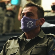 Major Juliano Amaral da Brigada Militar sentado com uma máscara roxa com o símbolo das patrulhas maria da penha