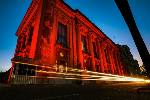 Foto do Palácio Piratini iluminado com luzes vermelhas. 