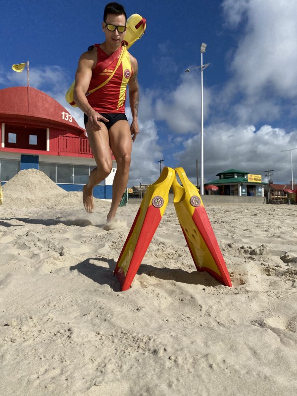 Bombeiro militar, com uniforme de guarda-vidas, em ação na praia
