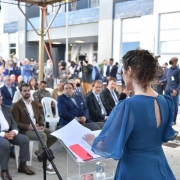 Diretora-geral do IGP, Heloísa Kuser, de vestido azul, em pé, diante de um púlpito de acrílico transparente e segurando um microfone, fala diante da plateia de autoridades e servidores durante a inauguração do Crepec-Sul.