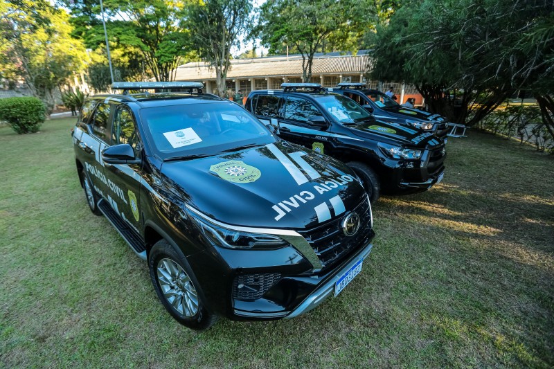 Três viaturas zero quilômetro da Polícia Civil estacionadas lado a lado em um gramado no complexo da Cidade da Polícia.