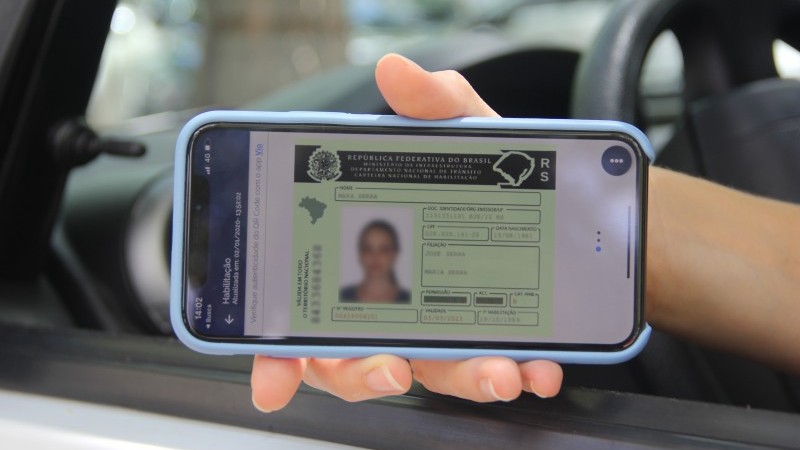 Mão feminina, segurando um aparelho celular com o aplicativo da Carteira Digital de Trânsito