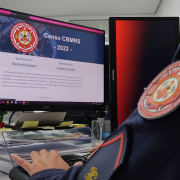 Foto de uma tela de computador mostra a página onde serão preenchidos os dados do 1º Censo do CBMRS. Em primeiro plano, à direita, aparece uma parte do ombro de um militar do CBMRS com o logo da corporação e uma divisa de soldado.