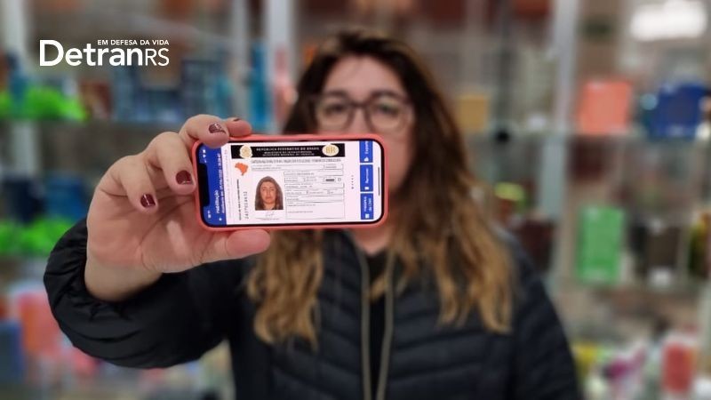 Mulher segurando celular e na tela aparece a NH digital
