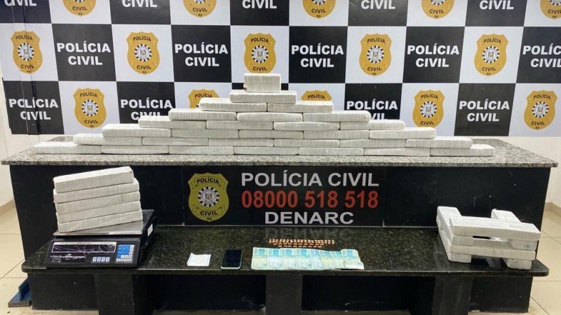 Foto mostra mesa com drogas, dinheiro e celular apreendidos pela Polícia Civil.