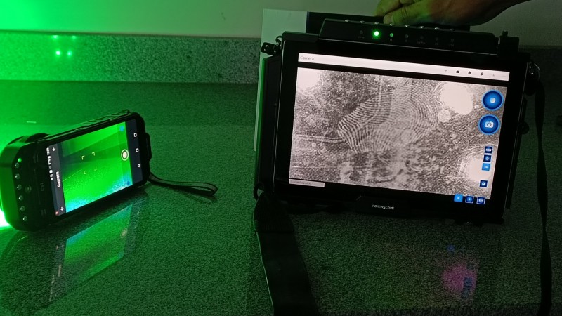 Demonstração do funcionamento dos novos equipamentos do IGP. Na tela do tablet, uma digital aparece nítida, enquanto o celular emite luz verde.