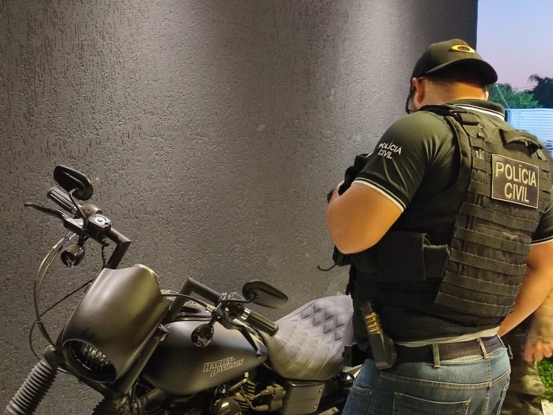 A foto mostra o policial apreendendo a moto 