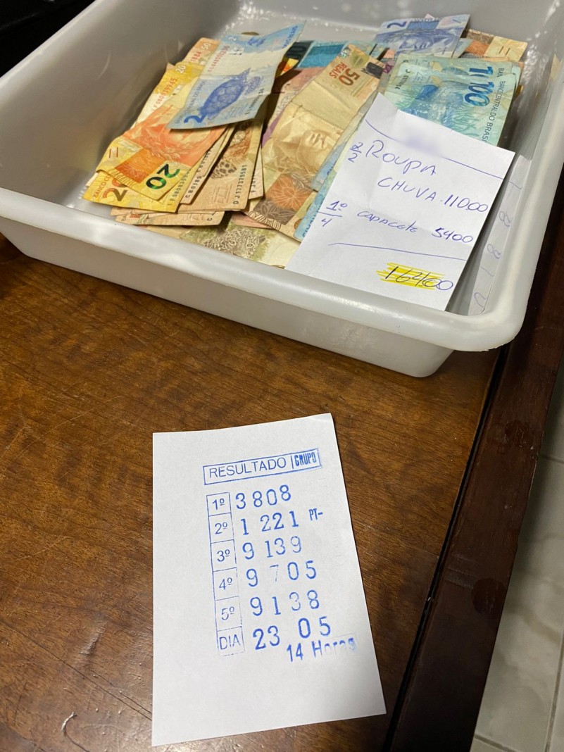 Foto mostra cédulas de dinheiro acompanhadas de papel com anotações e resultado de jogo do bicho.