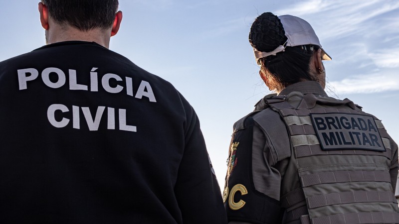 Policial Civil e Brigadiana de costas e observando à cidade