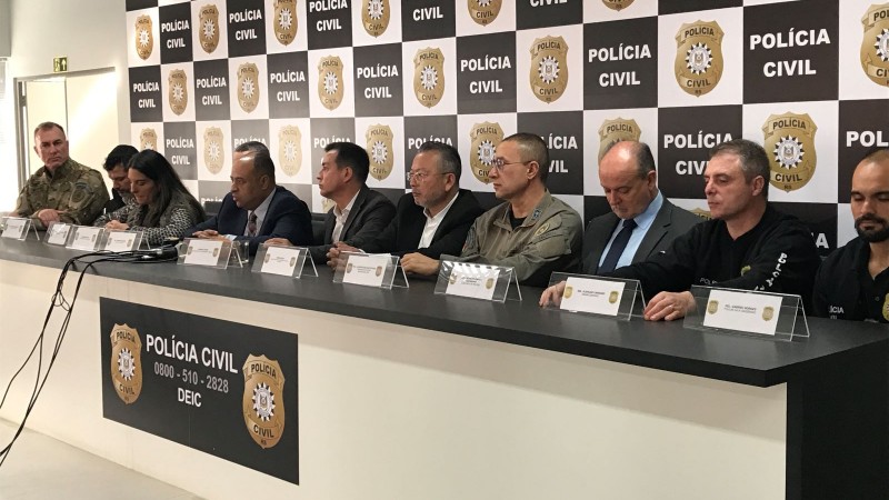 Foto mostra várias autoridades sentadas à mesa durante coletiva de imprensa da Polícia Civil