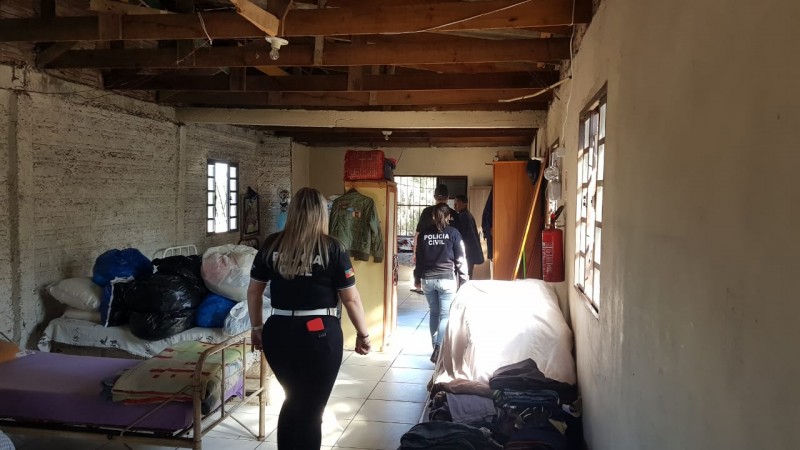 Foto mostra interior de quarto bagunçado, com camas desfeitas e paredes expostas.