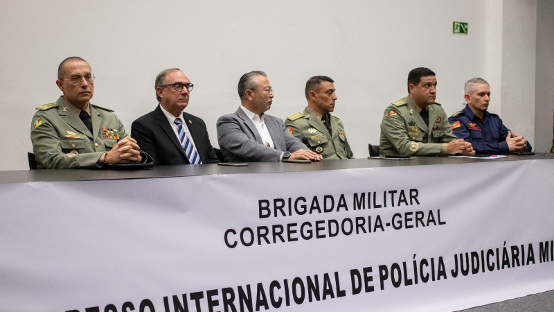 Foto mostra seis homens sentados em mesa de congresso.