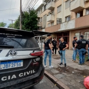 Foto mostra viatura e agentes da Polícia Civil em frente a condomínio onde foi realizada operação. 